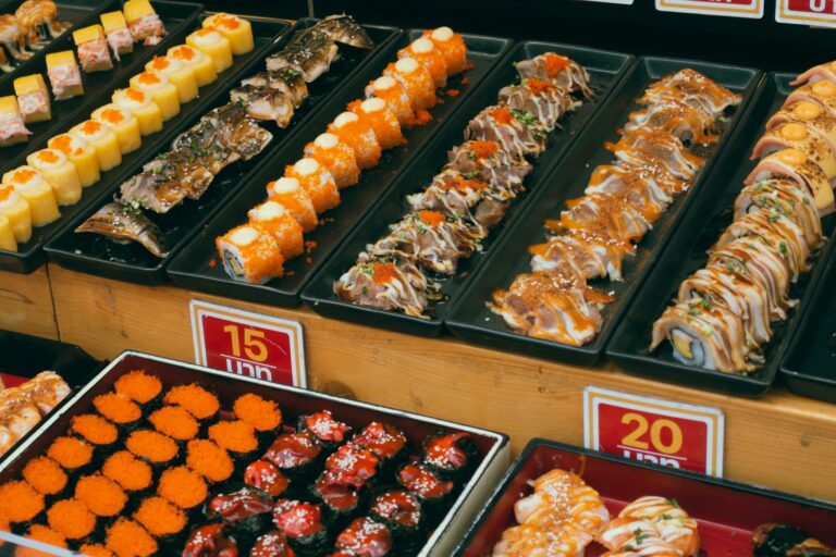 A colorful array of sushi platters at a buffet, showcasing assorted rolls and seafood delicacies.