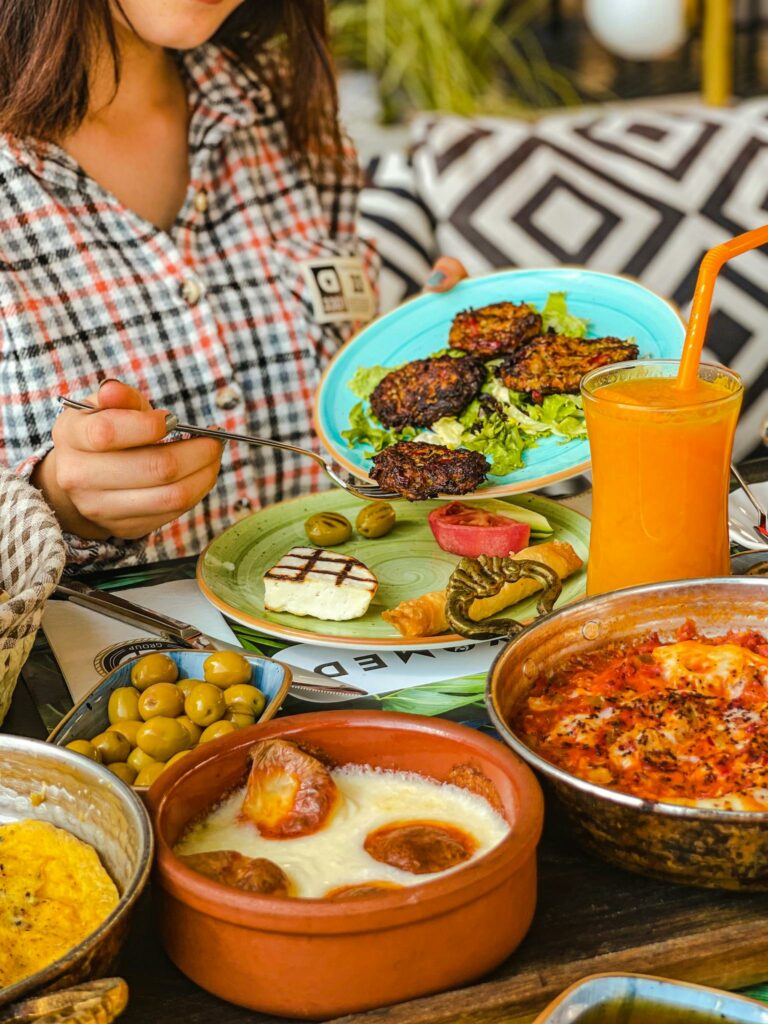 Mediterranean feast with diverse dishes and fresh orange juice on a wooden table.