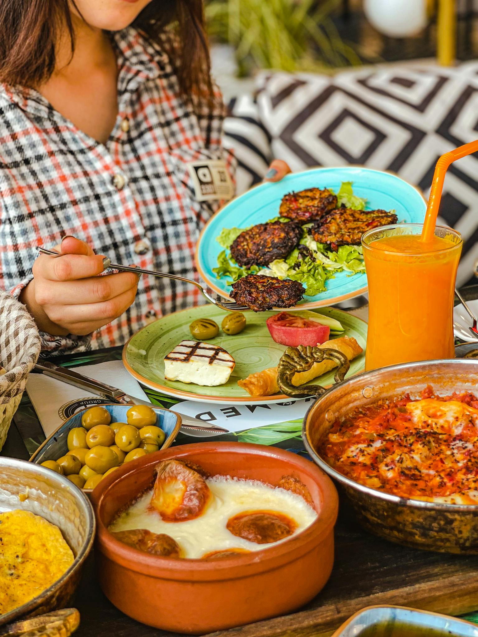 Mediterranean feast with diverse dishes and fresh orange juice on a wooden table.