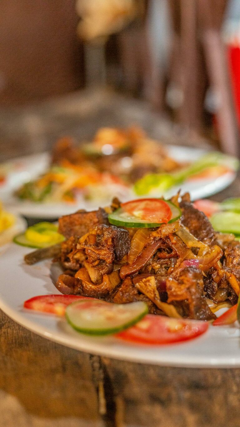 Mouth-watering beef dish with sliced vegetables on a white plate indoors.